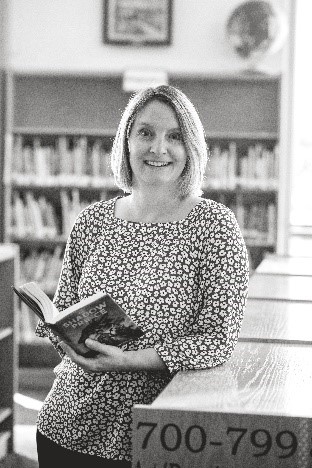 Tanya Parrott middle school librarian leaning against bookshelf