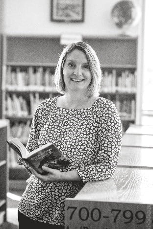 Tanya Parrott middle school librarian leaning against bookshelf